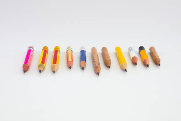 Seven colored pencils in shades of red, orange, and yellow, sit in a semi-circle on black.