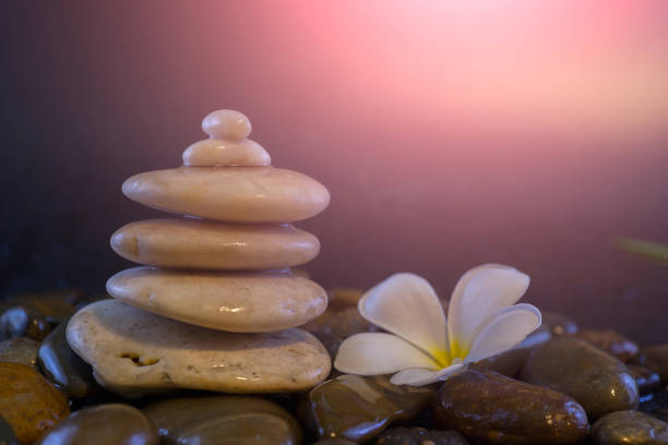 Relaxing ideas, white stones stacked with balance and refreshing white flowers against the backdrop of blurred rocks and light backgrounds, colors and soft colors.