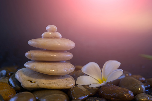 Relaxing ideas, white stones stacked with balance and refreshing white flowers against the backdrop of blurred rocks and light backgrounds, colors and soft colors.