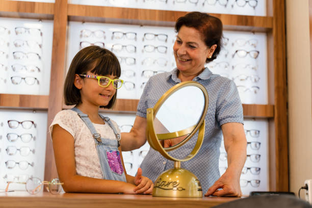 미소 짓는 소녀 고객이 광학 상점에서 안경을 선택합니다. - optometrist store retail glasses 뉴스 사진 이미지