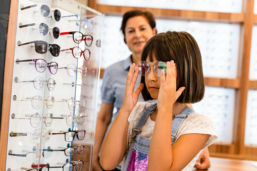 optician explaining and selling eyeglasses to young woman girl customer in optical shop store. Eyecare concept
