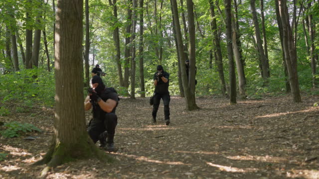 SWAT team aiming with weapons, while practise the mission at the forest