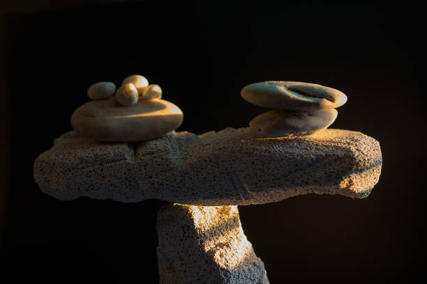 Balance equilibrium concept with natural stones. Comparison and equivalence of the two weights, light on the object and a black background.