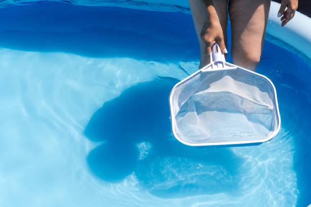 istock Woman cleaning her home's pool with a net 1411466412