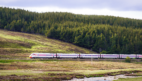 Moray, Scotland - Side view of an LNER Azuma high speed train travelling at speed along a hillside in the Scottish Highlands.