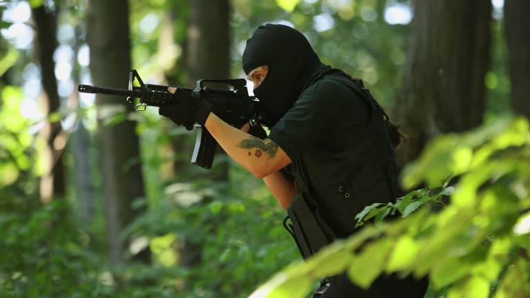 Man from SWAT team aiming with weapon, during mission at the forest