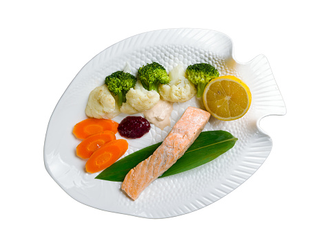 Salmon steak on steam with steamed vegetables isolated on white background top view
