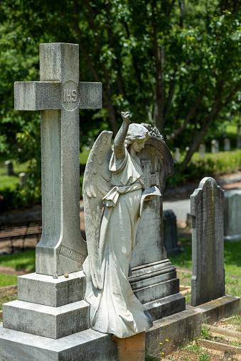 Tombstones in graveyard/burial ground from the 1800s on a sunny summer day in July. The image is part of a series of images of graveyard tombstone/sculptures captured with a full frame digital camera with a sharp, short 85mm prime telephoto lens at f/2.8 and low ISO (100) resulting in large, noiseless images of professional quality.