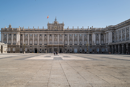 Madrid, Spain -- June 18, 2022. A wide angle photo looking over a courtyard of the Royal Palace and onto the palace itself.