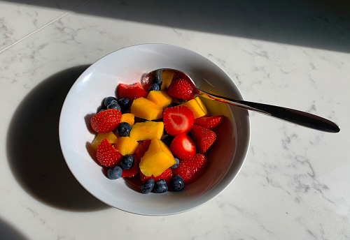 A bowl of healthy mixed fruit on a kitchen surface.