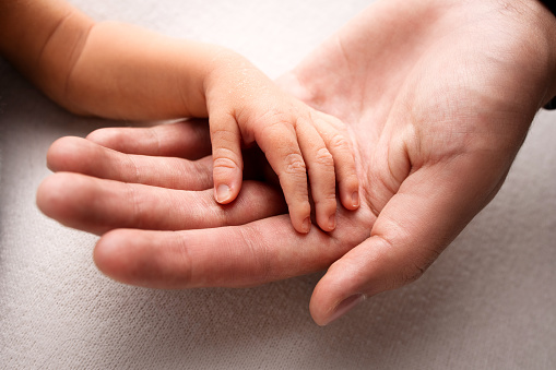 The baby is holding on to the mother's finger. Hands close-up. Black and white photo. Side view. Concept of motherhood and children's day. High quality photo