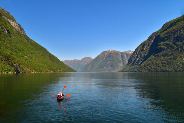 Couple kayaking across fjord in Geiranger region, Norway stock photo