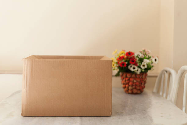 Open cardboard box with flowers on the side. Delivery box being opened. Box concept. Unboxing concept. Space for text.