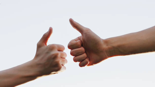 istock two hands shows thumbs up on blue sky background. Big finger up. Approval 1411475429