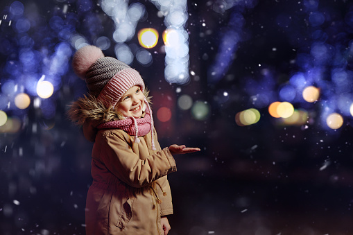 Teenage girl walking outdoors during the blizzard. She is admiring the heavy snowfall and the wind.\nShot with Canon R5.