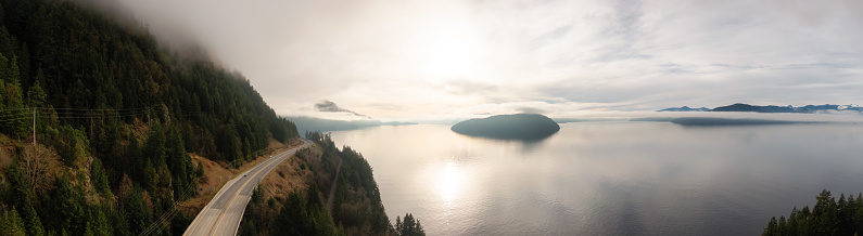 Sea to Sky Highway in Howe Sound on West Coast Pacific Ocean during cloudy winter evening before sunset. Aerial Panoramic View. Near Squamish and Vancouver, British Columbia, Canada.