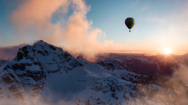 istock Dramatic Mountain Landscape covered in clouds and Hot Air Balloon Flying 1411476731