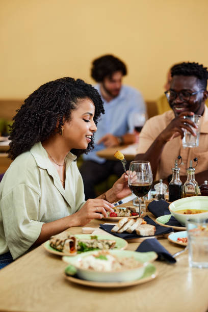 istock A woman is eating her dinner in a restaurant while sitting at the dinner table with her friends. 1411477667