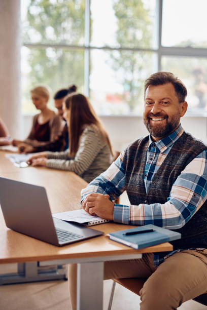 istock HAppy mature student using laptop in the classroom and looking at camera. 1411477855
