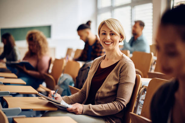 istock Happy mid adult student writing notes during a lecture and looking at camera. 1411477942