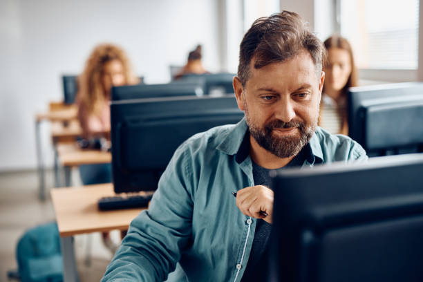 mature man attending computer class at the university. - night school imagens e fotografias de stock