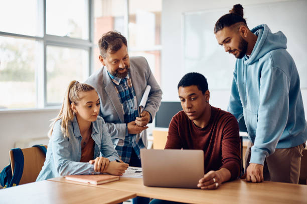 istock Multiracial group of students cooperating with their professor while e-learning on laptop in the classroom. 1411478329