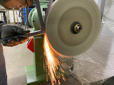 Worker grinding metal with sparks in workshop