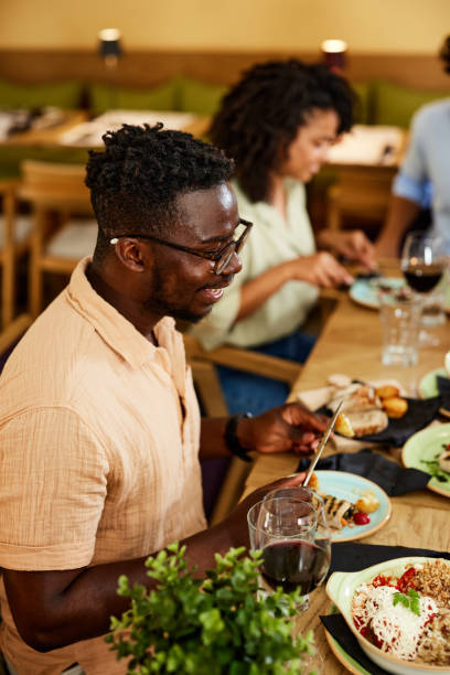 istock An African man sits in a restaurant and eats lunch with friends. 1411479298