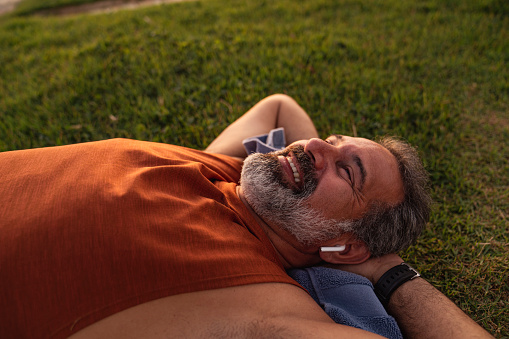 A mature athlete is lying on the grass and taking a break after a good workout outdoors