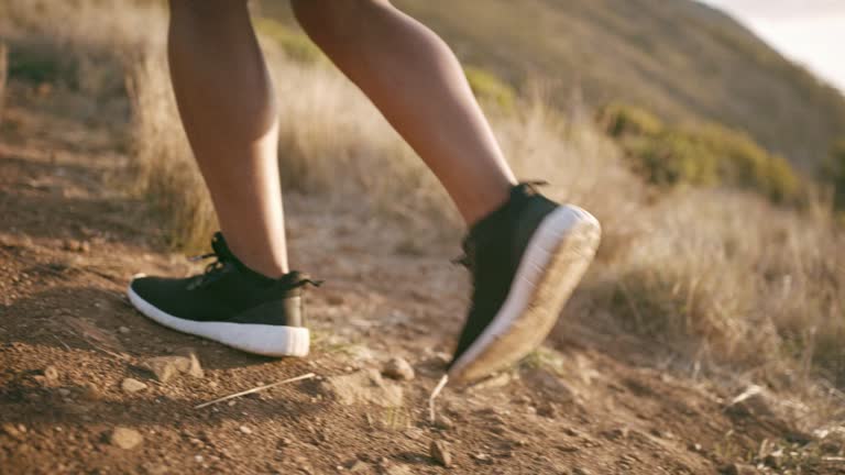 Closeup of two people hiking on the mountains. Active adults on an adventure walking through rocky path way on a hill wearing sneakers and tights