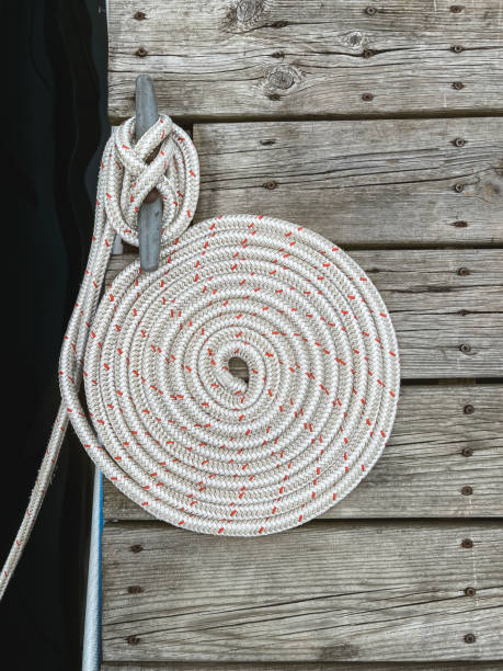 cuerda de estilo náutico enrollada en un círculo espiral en un muelle de barcos - moored nautical equipment circle rope fotografías e imágenes de stock