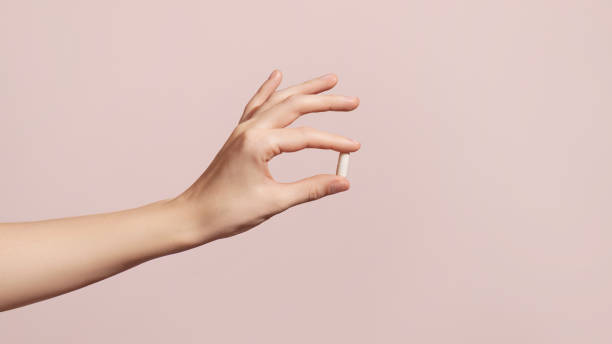 Hand holding the supplements on pink background stock photo