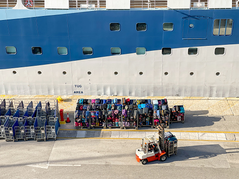 Athens, Greece - may 2022: Crew of a cruise ship unloading trolleys stacked with luggage at the end of a cruise