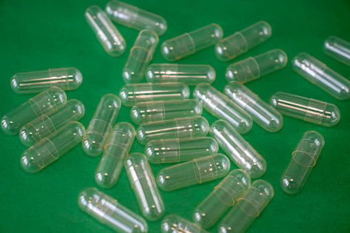 Empty Capsule Pill on a Bright Green Background. Freeze-dried Powder Filling Capsules.