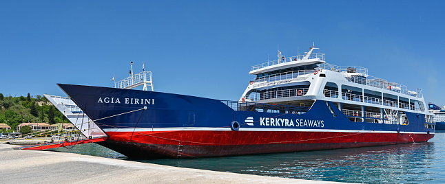 Corfu, Greece - June 2022: Panoramic view of a commercial car ferry with vehicle ramp lowered in the harbour of Corfu town. The ship is operated by Kerkyra Seaways.