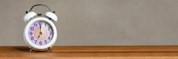 istock Seven o'clock on the alarm. A white alarm clock stands on a wooden table. The clock hand points to seven o'clock. Switching to summer or winter time. Set an alarm for 7:00 or 19:00. copy space 1411485033