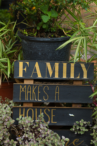 Gold colored letters FAMILY on black wood with additional text family makes a home