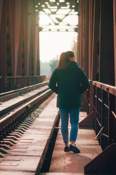 istock Lonely young woman walking on a railway bridge 1411485121