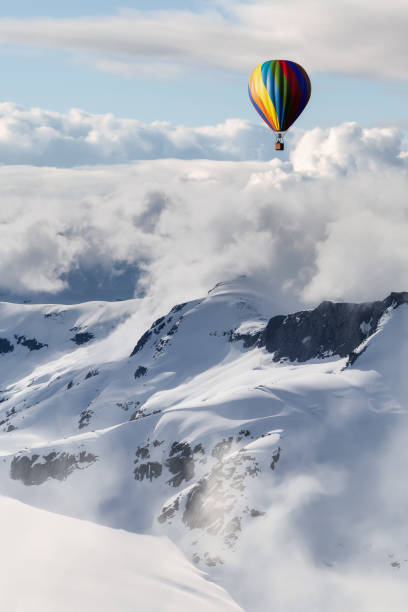 istock Dramatic Mountain Landscape covered in clouds and Hot Air Balloon Flying 1411486143