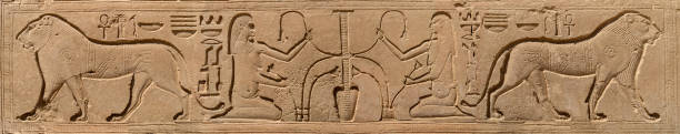 Two figures of god Hapi representing upper and lower Egypt tying lotus and papyrus around Nile between two Lions on the wall of Karnak temple .Luxor Egypt .