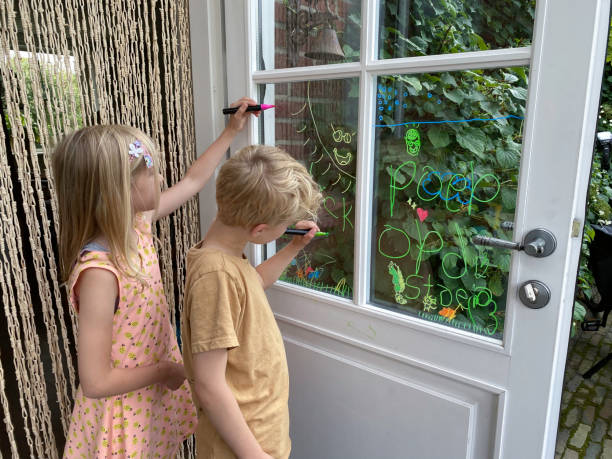 Brother and sister children making a window paint