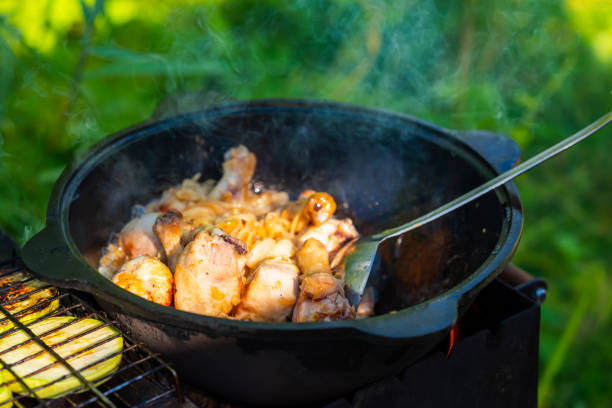 Fresh, juicy chicken legs are fried with onions in a cast-iron cauldron in vegetable oil. The chicken is thwarted with a scoop. Georgian chakhokhbili with chicken. Small depth of field. Food in nature las piernas de pollo frescas y jugosas se fríen con cebollas en un caldero de hierro fundido en aceite vegetal. el pollo se frustra con una cucharada. chakhokhbili georgiano con pollo. pequeña profundidad de campo. alimentos en la naturaleza