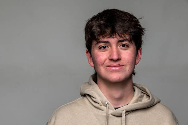 Smiling teenage boy front mugshot on gray background stock photo