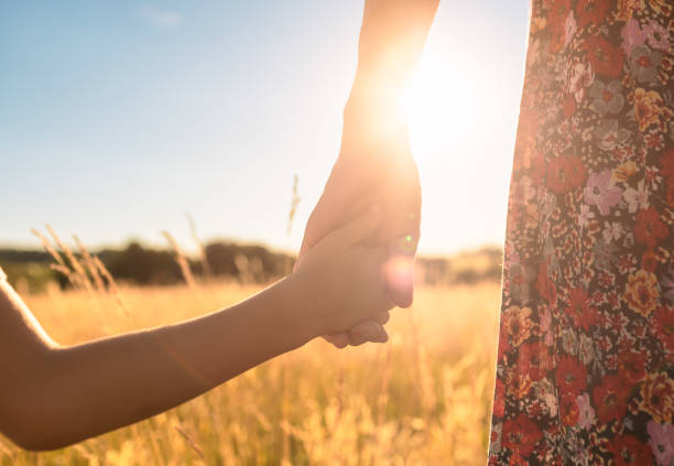 istock Mother and child holding hands in field at sunset 1411491724