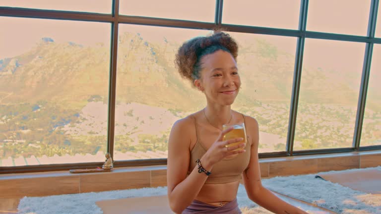 Active woman smelling her tea in a modern and peaceful exercise facility. Spiritual female appreciating her drink sitting on a glass building. Fit and healthy enjoying her favorite beverage