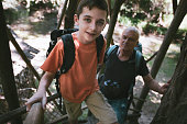 Grandfather and grandson climbing a watchtower in the forest