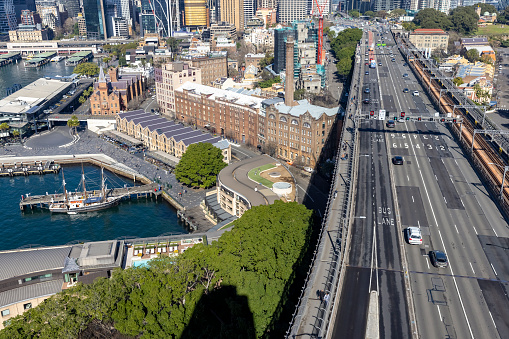 Sydney ferry with commuters passing the Sydney Harbour Bridge, heading for Circular Quay and business district in early  golden morning light. The single-span arch bridge also known as the \