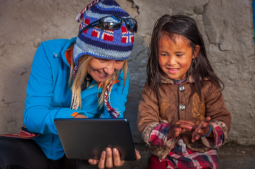 A young woman shows a little girl how to use a digital tablet, Mount Everest National Park. This is the highest national park in the world, with the entire park located above 3,000 m ( 9,700 ft).