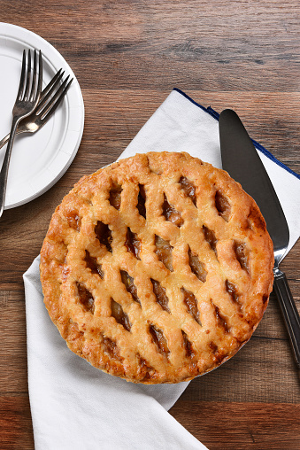 A fresh baked apple pie, server with plates and forks. The dessert is part of a typical Thanksgiving Day Feast.
