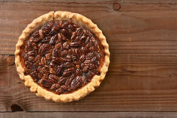 A fresh baked pecan pie on a rustic wood table with copy space.